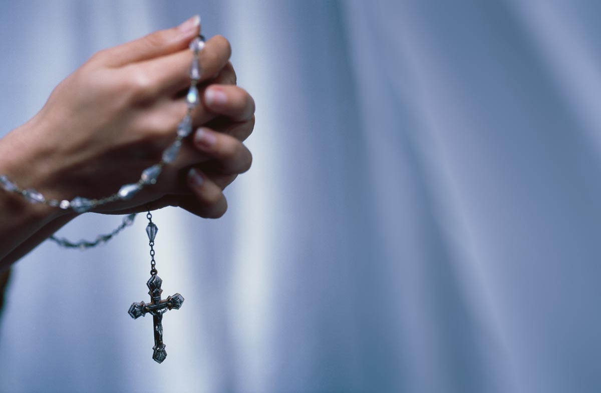 hands holding a rosary in prayer